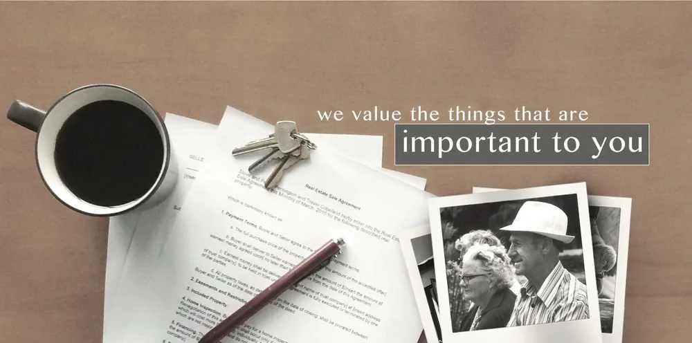 Coffee, house keys and a real estate agreement on a desk beside family photographs